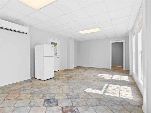 1322 Oahu Dr, Tiki Island, TX 77554 - unfurnished room with a wall mounted AC, a paneled ceiling, and light stone finish floors