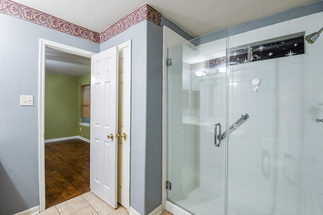 15522 Noble Brook Ct, Houston, TX 77049 - bathroom featuring a shower stall, tile patterned floors, a textured ceiling, and baseboards