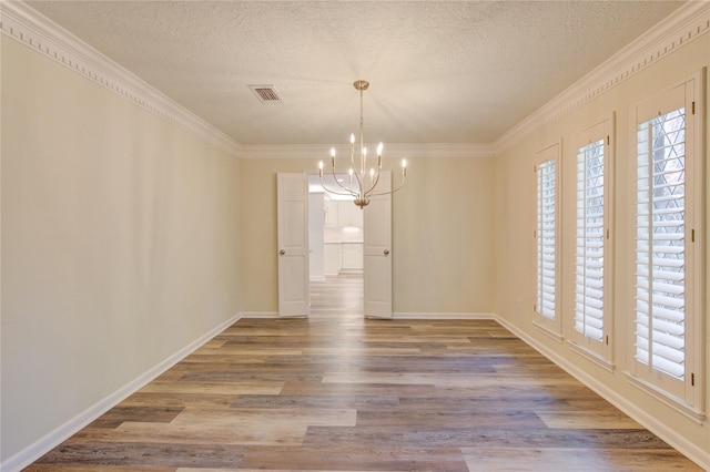 unfurnished dining area featuring a chandelier, ornamental molding, wood finished floors, a textured ceiling, and baseboards