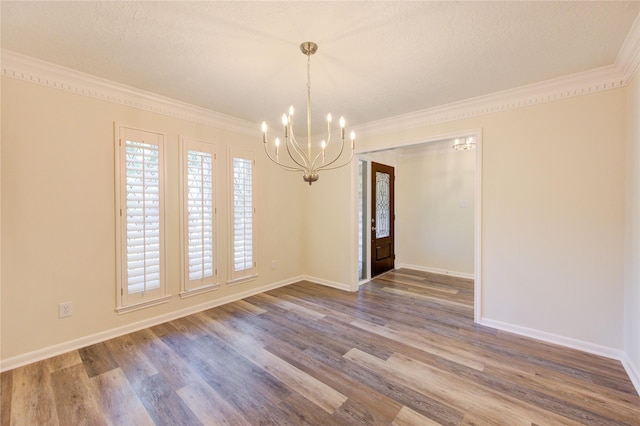 unfurnished dining area featuring a chandelier, wood finished floors, baseboards, ornamental molding, and a textured ceiling