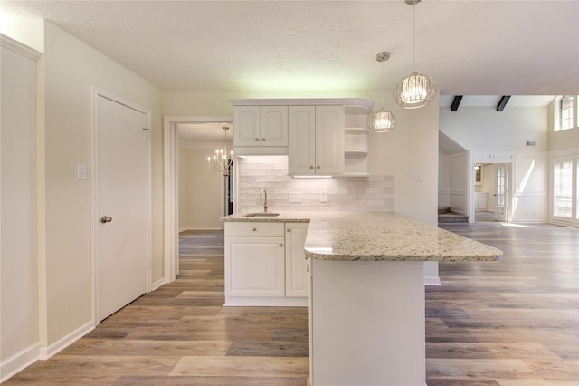 kitchen featuring a chandelier, open shelves, backsplash, a peninsula, and light wood-style floors