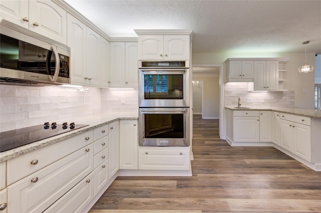 kitchen featuring stainless steel appliances, a sink, tasteful backsplash, open shelves, and a textured ceiling
