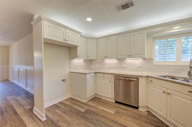 kitchen featuring dishwasher, a sink, light stone countertops, light wood finished floors, and a textured ceiling