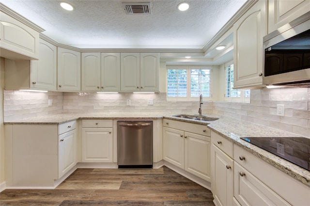kitchen featuring appliances with stainless steel finishes, light stone countertops, a sink, a textured ceiling, and recessed lighting