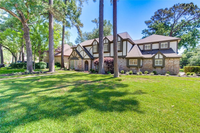 tudor house featuring a front yard, stucco siding, and brick siding