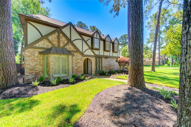 tudor house with stucco siding, brick siding, and a front lawn