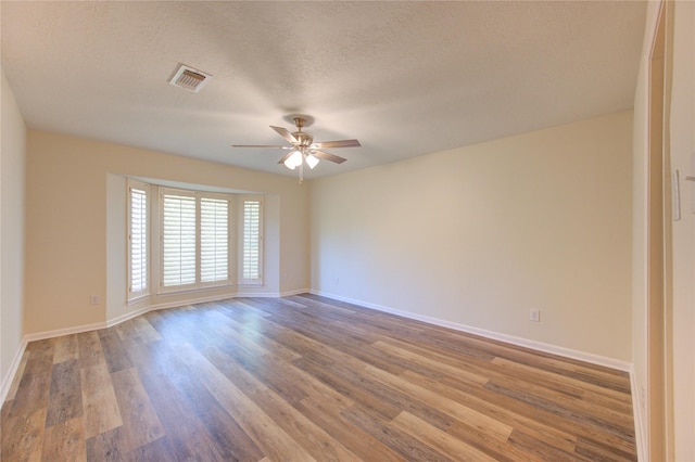 spare room featuring a ceiling fan, wood finished floors, baseboards, and a textured ceiling