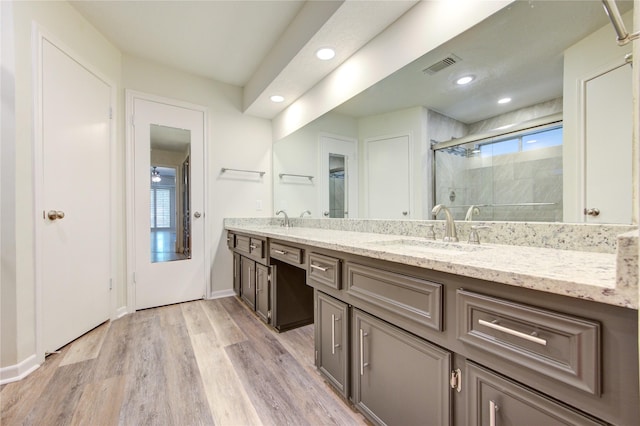 full bath featuring a shower stall, double vanity, wood finished floors, recessed lighting, and baseboards