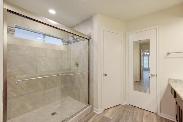 full bath featuring wood finished floors, a stall shower, vanity, baseboards, and recessed lighting