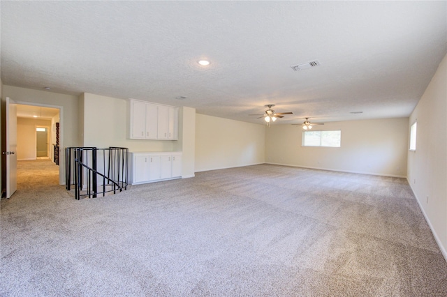 empty room featuring light carpet, a ceiling fan, and baseboards