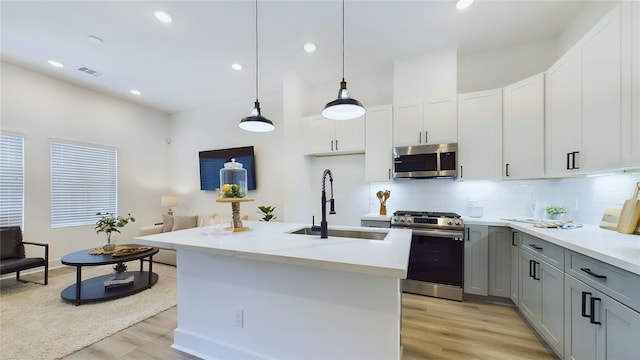 3019 Jensen Springs Ln, Houston, TX 77026 - kitchen featuring appliances with stainless steel finishes, a sink, light wood-style flooring, tasteful backsplash, and recessed lighting