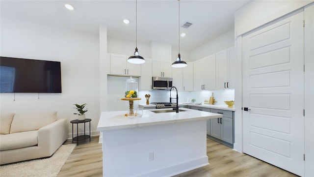 3019 Jensen Springs Ln, Houston, TX 77026 - kitchen featuring stainless steel microwave, light wood-style flooring, hanging light fixtures, white cabinets, and recessed lighting