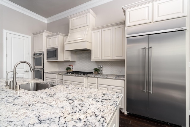 831 Dunleigh Meadows Ln, Houston, TX 77055 - kitchen with built in appliances, a sink, crown molding, dark wood-style floors, and light stone counters