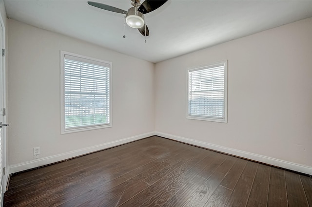 empty room featuring healthy amount of natural light, dark wood-style floors, a ceiling fan, and baseboards