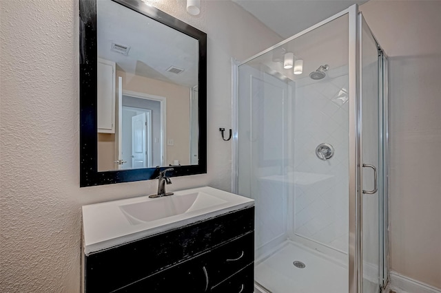 bathroom with a stall shower, a textured wall, and vanity