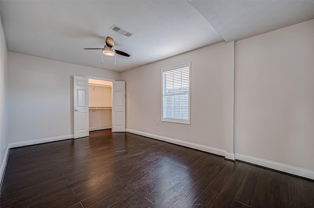 unfurnished bedroom featuring baseboards, wood finished floors, a ceiling fan, and a spacious closet
