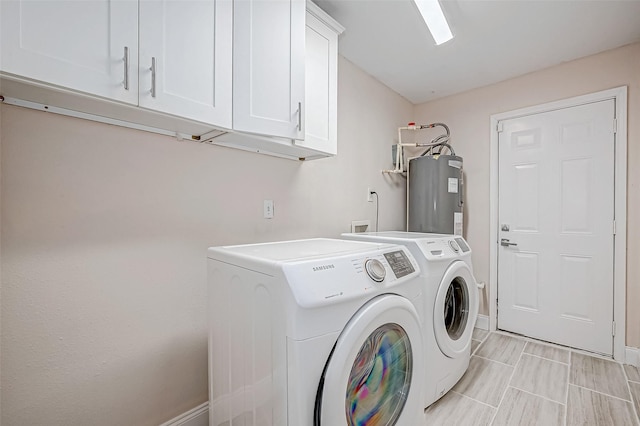 laundry room featuring water heater, cabinet space, washer and clothes dryer, and baseboards