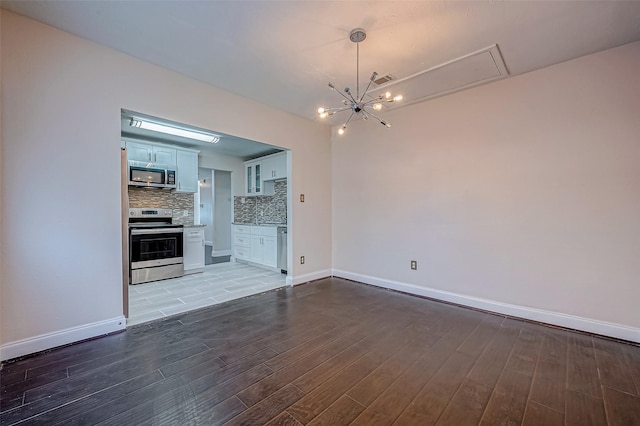 unfurnished living room with wood finished floors, a chandelier, and baseboards
