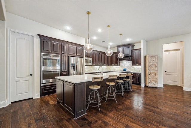 5119 Kendalia Cloud Ln, Fulshear, TX 77441 - kitchen with stainless steel appliances, dark brown cabinets, a sink, backsplash, and a center island with sink