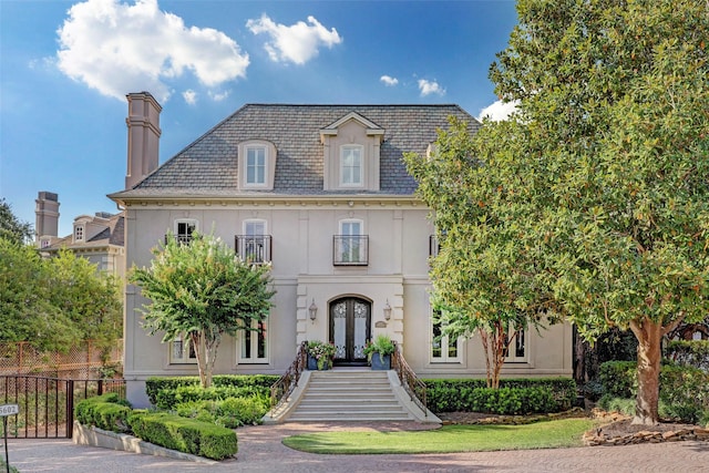5602 Indian Cir, Houston, TX 77056 - view of front facade with french doors, stucco siding, a chimney, and a high end roof