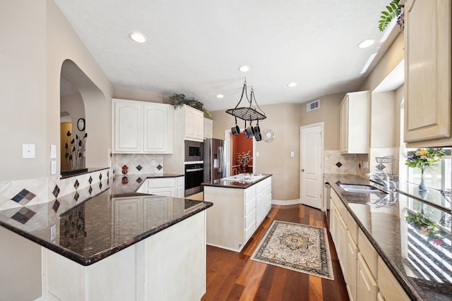 7719 Allegro Dr, Houston, TX 77040 - kitchen featuring appliances with stainless steel finishes, a sink, a kitchen island, dark wood-style flooring, and backsplash