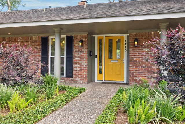 1415 Lehman St, Houston, TX 77018 - view of exterior entry featuring brick siding, a shingled roof, a porch, and a chimney