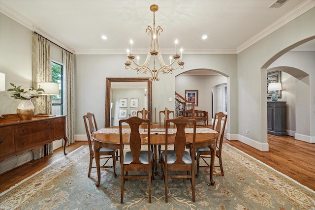 4504 Birch St, Bellaire, TX 77401 - dining room with arched walkways, wood finished floors, a chandelier, baseboards, and ornamental molding