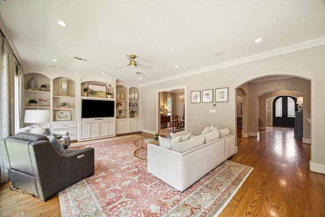 4504 Birch St, Bellaire, TX 77401 - living room featuring arched walkways, a ceiling fan, ornamental molding, baseboards, and wood finished floors