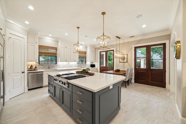 4504 Birch St, Bellaire, TX 77401 - kitchen featuring stainless steel appliances, white cabinetry, a sink, decorative backsplash, and a center island
