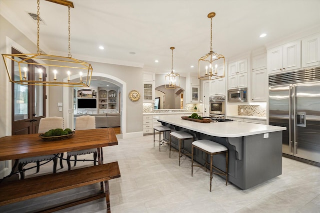 4504 Birch St, Bellaire, TX 77401 - kitchen featuring built in appliances, a chandelier, arched walkways, light countertops, and a kitchen island
