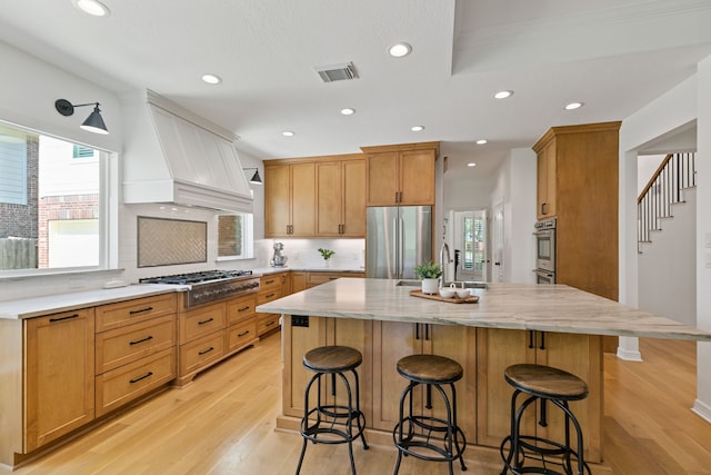 13911 Falcon Heights Dr, Cypress, TX 77429 - kitchen featuring appliances with stainless steel finishes, a sink, a spacious island, light wood finished floors, and recessed lighting