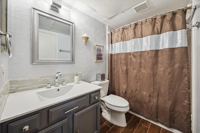 1860 White Oak Dr Unit 246, Houston, TX 77009 - full bathroom with wood finished floors, a textured wall, toilet, vanity, and backsplash