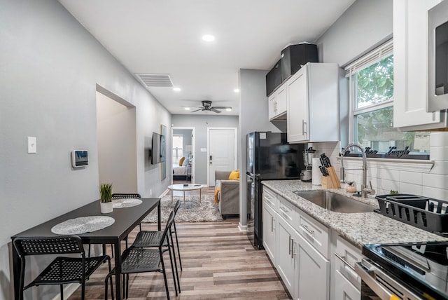 3409 Providence St, Houston, TX 77020 - kitchen with a sink, light wood-style flooring, backsplash, a ceiling fan, and light stone counters