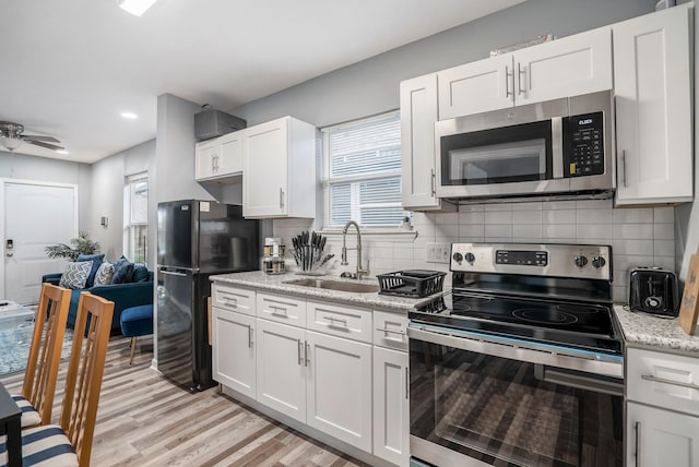 3409 Providence St, Houston, TX 77020 - kitchen featuring appliances with stainless steel finishes, a sink, light wood-style floors, backsplash, and recessed lighting