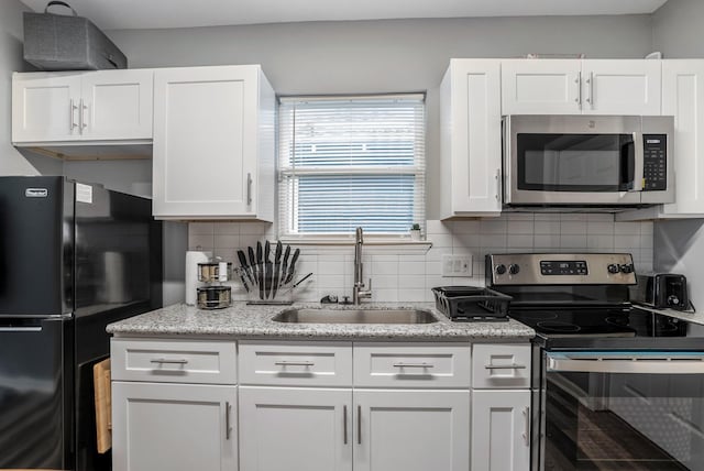 3409 Providence St, Houston, TX 77020 - kitchen featuring stainless steel appliances, a sink, white cabinets, tasteful backsplash, and light stone counters