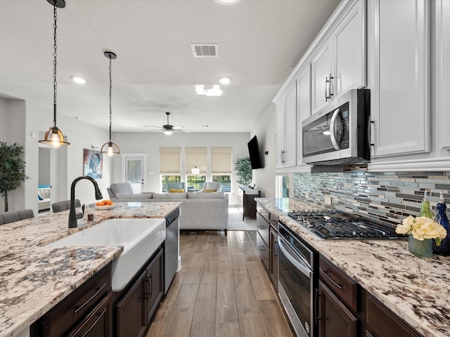 11715 Tranquility Summit Dr, Cypress, TX 77433 - kitchen featuring appliances with stainless steel finishes, a sink, white cabinetry, dark brown cabinetry, and ceiling fan
