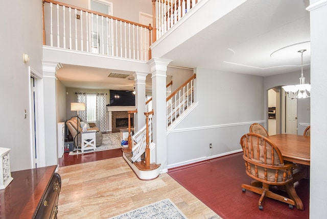 19711 Arbor Creek Dr, Katy, TX 77449 - dining area with a fireplace with raised hearth, decorative columns, a towering ceiling, arched walkways, and stairway