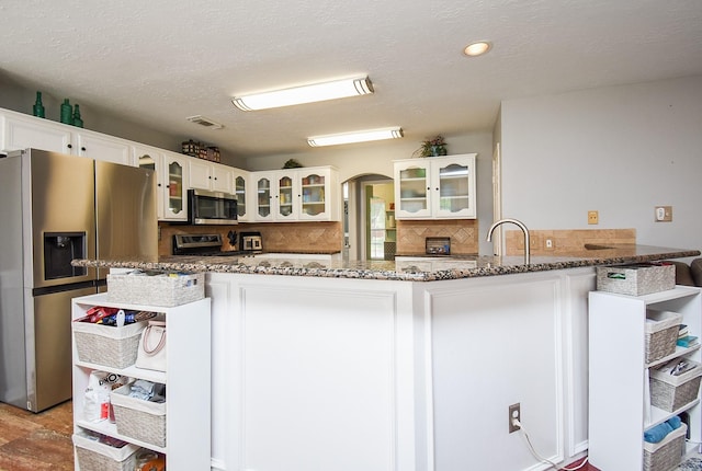 19711 Arbor Creek Dr, Katy, TX 77449 - kitchen with appliances with stainless steel finishes, stone counters, white cabinets, decorative backsplash, and glass insert cabinets