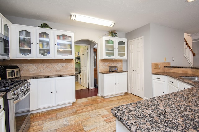 19711 Arbor Creek Dr, Katy, TX 77449 - kitchen featuring stainless steel appliances, tasteful backsplash, dark stone countertops, and white cabinets