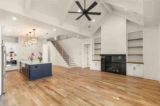 1038 W 31st St, Houston, TX 77018 - unfurnished living room with stairs, a fireplace, ceiling fan, light wood-type flooring, and beamed ceiling
