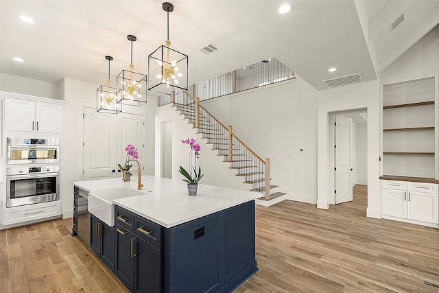 1038 W 31st St, Houston, TX 77018 - kitchen with a sink, light wood-style flooring, white cabinets, stainless steel double oven, and a chandelier