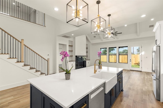 1038 W 31st St, Houston, TX 77018 - kitchen featuring stainless steel appliances, a sink, a chandelier, light wood finished floors, and light countertops