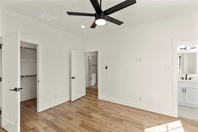 1038 W 31st St, Houston, TX 77018 - unfurnished bedroom featuring light wood-style floors, a sink, baseboards, and a walk in closet