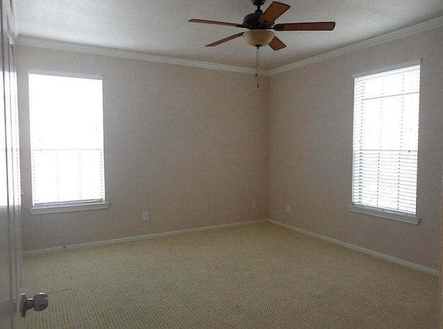 empty room with ornamental molding, a ceiling fan, baseboards, and light colored carpet
