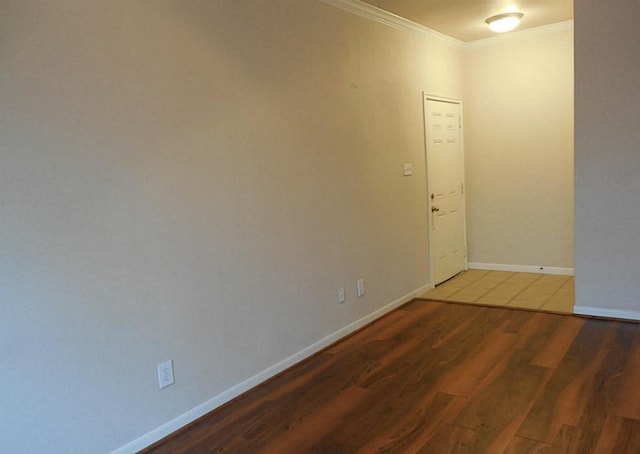 empty room featuring crown molding, wood finished floors, and baseboards