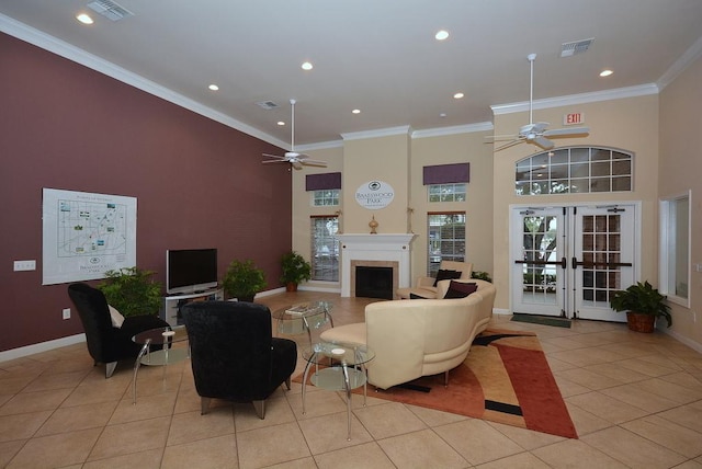 living area featuring ceiling fan, light tile patterned floors, a fireplace, ornamental molding, and a high ceiling