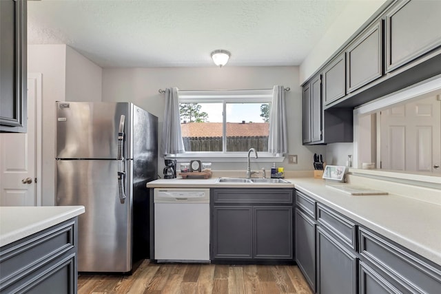 710 Razee Ct, Crosby, TX 77532 - kitchen featuring white dishwasher, freestanding refrigerator, a sink, gray cabinets, and light wood-style flooring