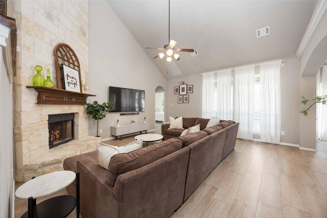 30427 Legacy Pines Dr, Spring, TX 77386 - living room featuring a fireplace, ceiling fan, high vaulted ceiling, arched walkways, and light wood finished floors