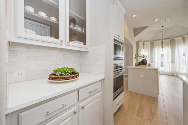 30427 Legacy Pines Dr, Spring, TX 77386 - kitchen with white cabinetry, glass insert cabinets, light wood-style flooring, stainless steel appliances, and backsplash