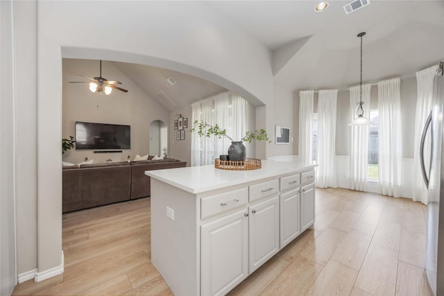 30427 Legacy Pines Dr, Spring, TX 77386 - kitchen with arched walkways, a ceiling fan, freestanding refrigerator, a kitchen island, and white cabinetry
